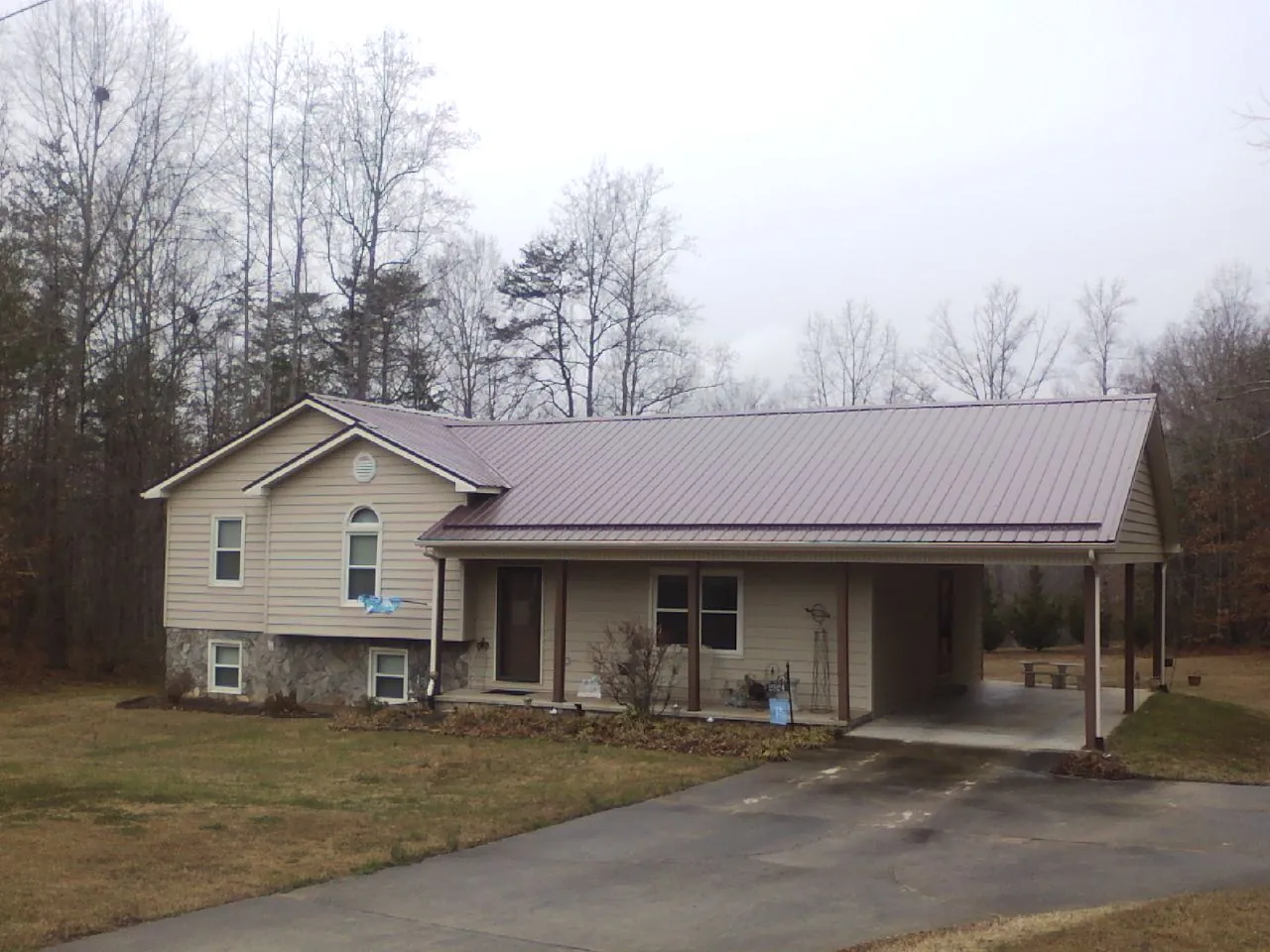 Burgundy metal roof on a tan split level home with an attached carport in Jacksonville