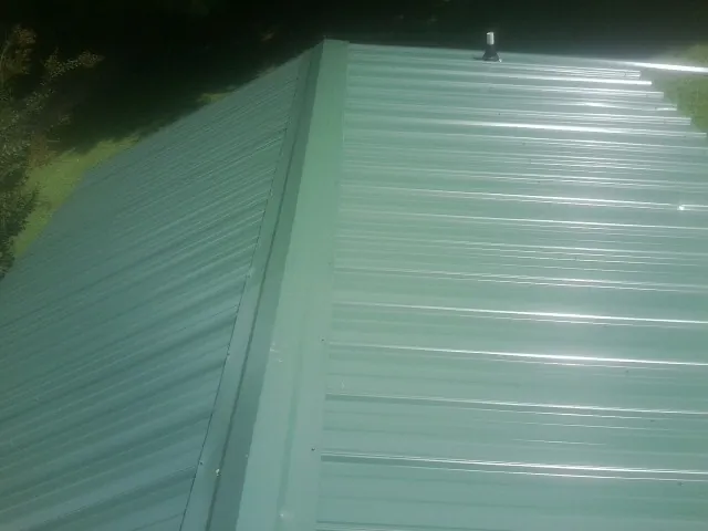 New green metal panels meeting at the ridge of a roof — Flat Roof Repair work by our crew in Jacksonville